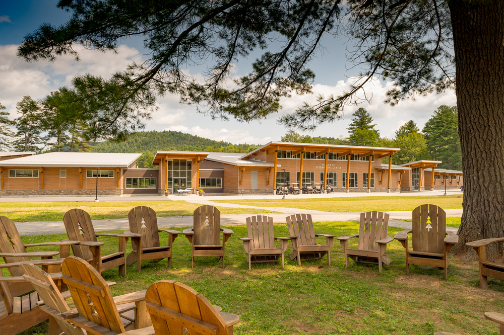A student life center with Nichiha’s VintageWood fiber cement cladding in the background with a circle of rustic wooden chairs in front of it.