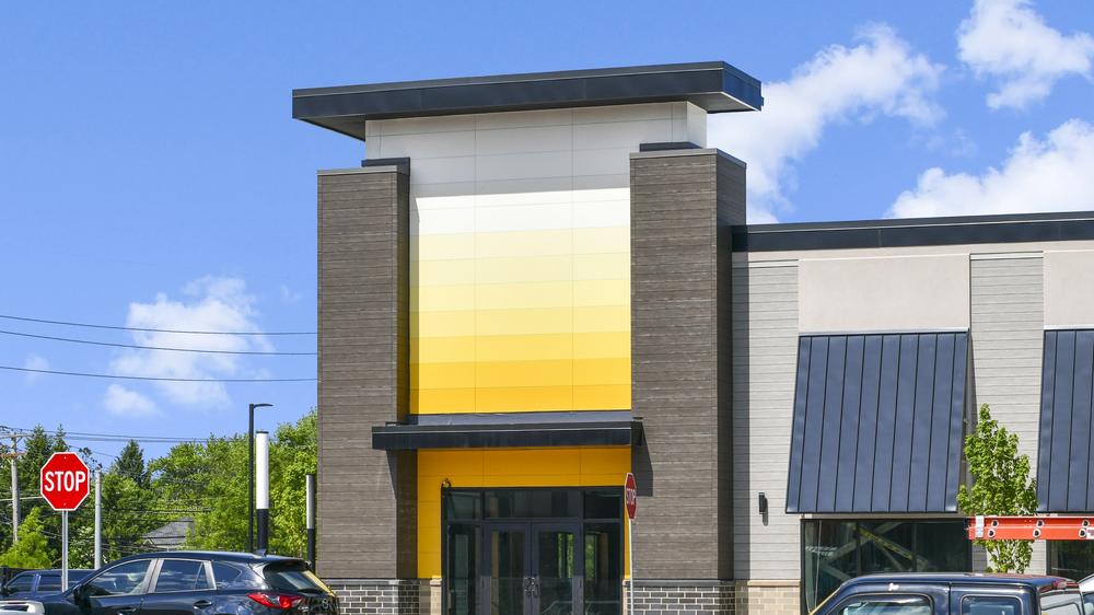 Looking at the exterior entryway featuring an ombre of yellow fiber cement siding from white at the top fading to dark yellow at the bottom.