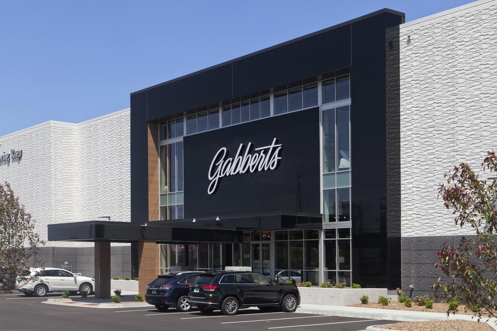 A sidelong view of the front of Gabberts retail store, showcasing the black reflective Miraia fiber cement siding and large vertical glass windows surrounded by stone cladding.