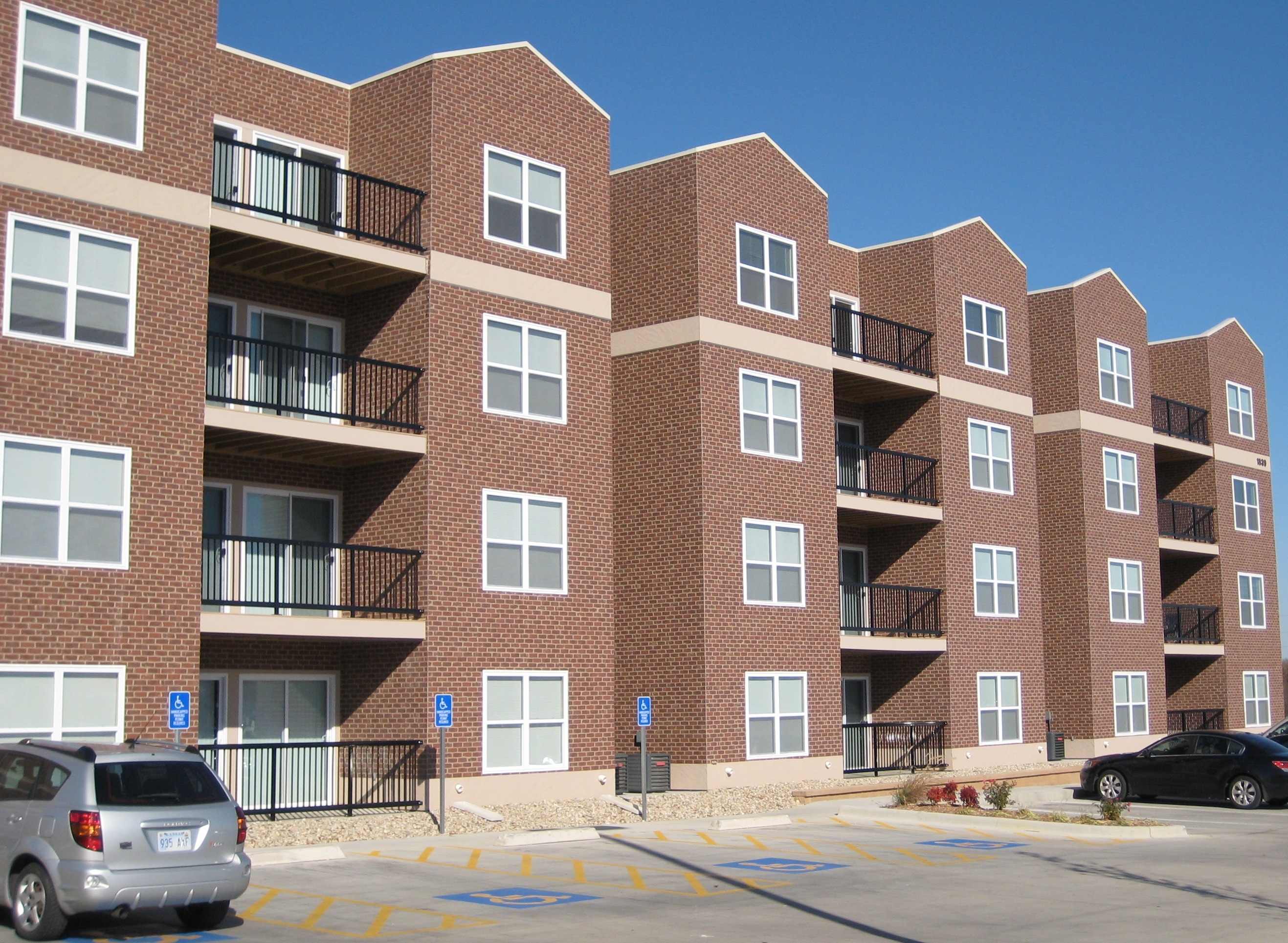 Parking lot view of student housing with brick exterior and large parking area.