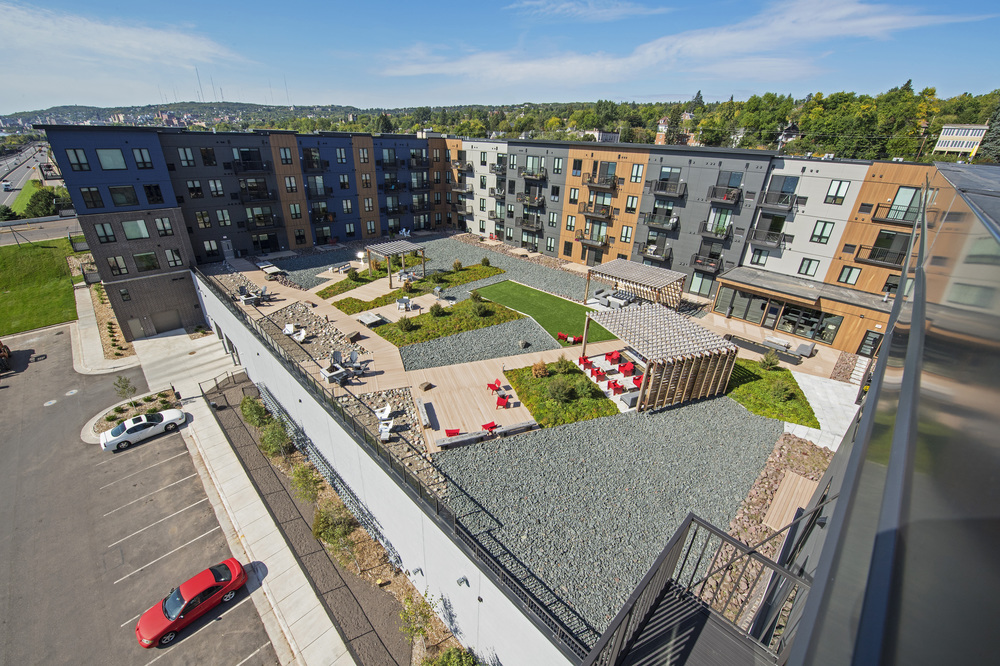 An aerial view of Endi apartment complex. The U-shaped complex surrounds a grass and gravel courtyard with various seating areas.