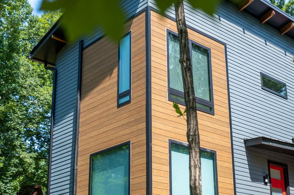 Corner of residential home showing mixed wood look and blue horizontal siding.