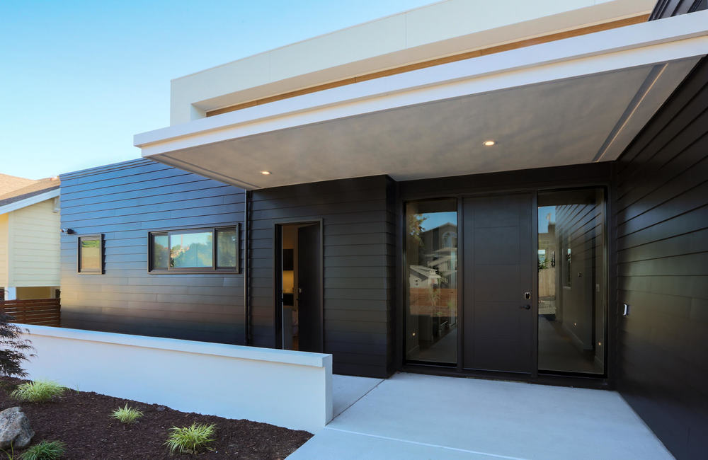 This one-story, black house has a concrete pad outside of the front door.
