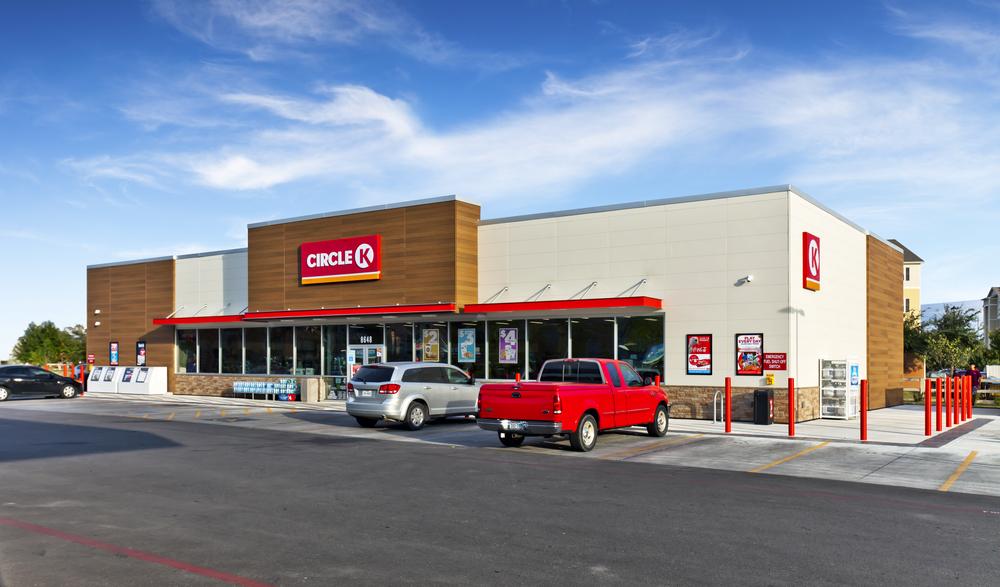 Convenience storefront of Circle K with red awning and white and wood look siding.