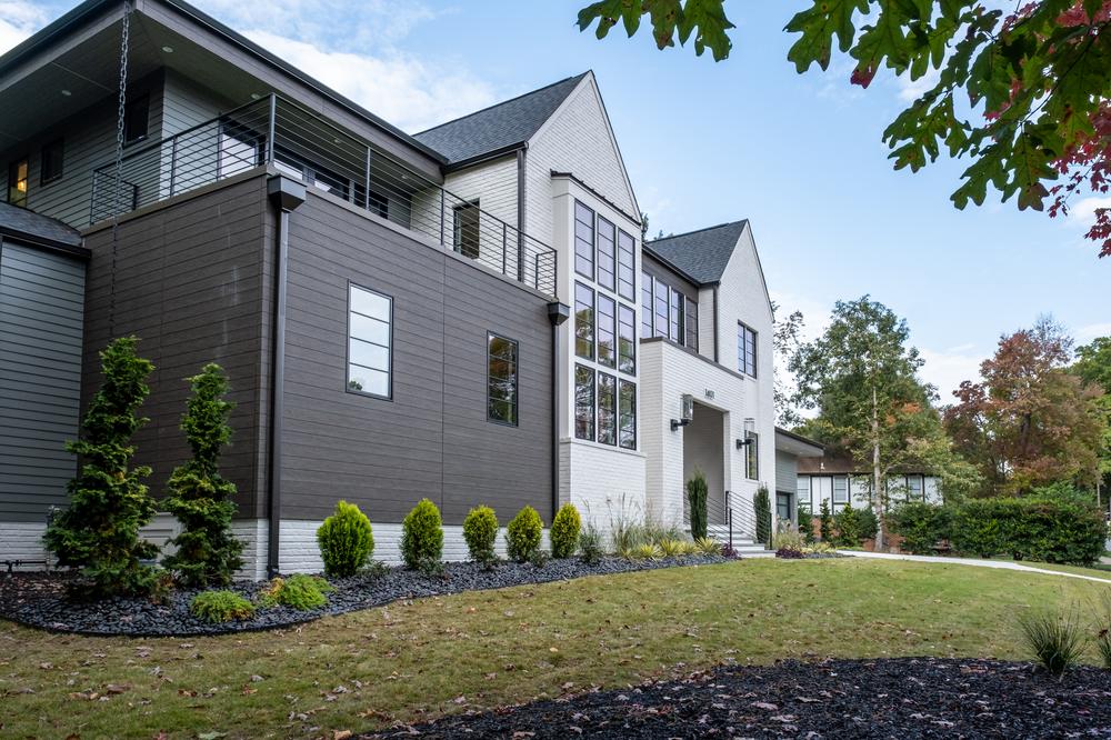 A dark brown and white home with large windows decorated with Nichiha’s fiber cement siding.