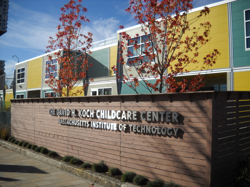 The sign for The David H. Koch Childcare Center at MIT with their yellow and blue building utilizing Nichiha&rsquo;s modular construction.