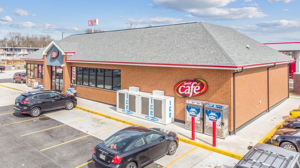 A faraway shot of Speedy Cafe convenience store with a gray roof, red and white logo, and brick-like cladding provided by Nichiha.