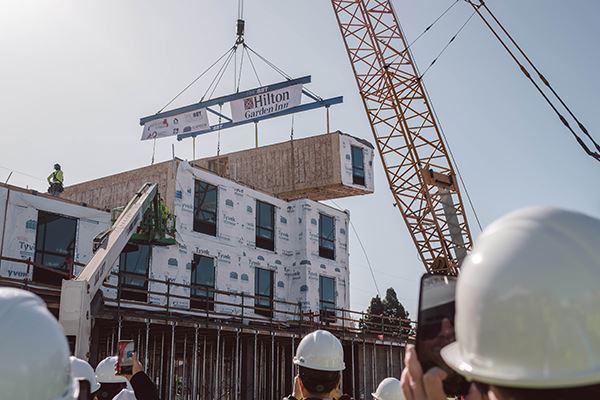 Modular box being craned into place for the Hilton Garden Inn San Jose with onlookers watching