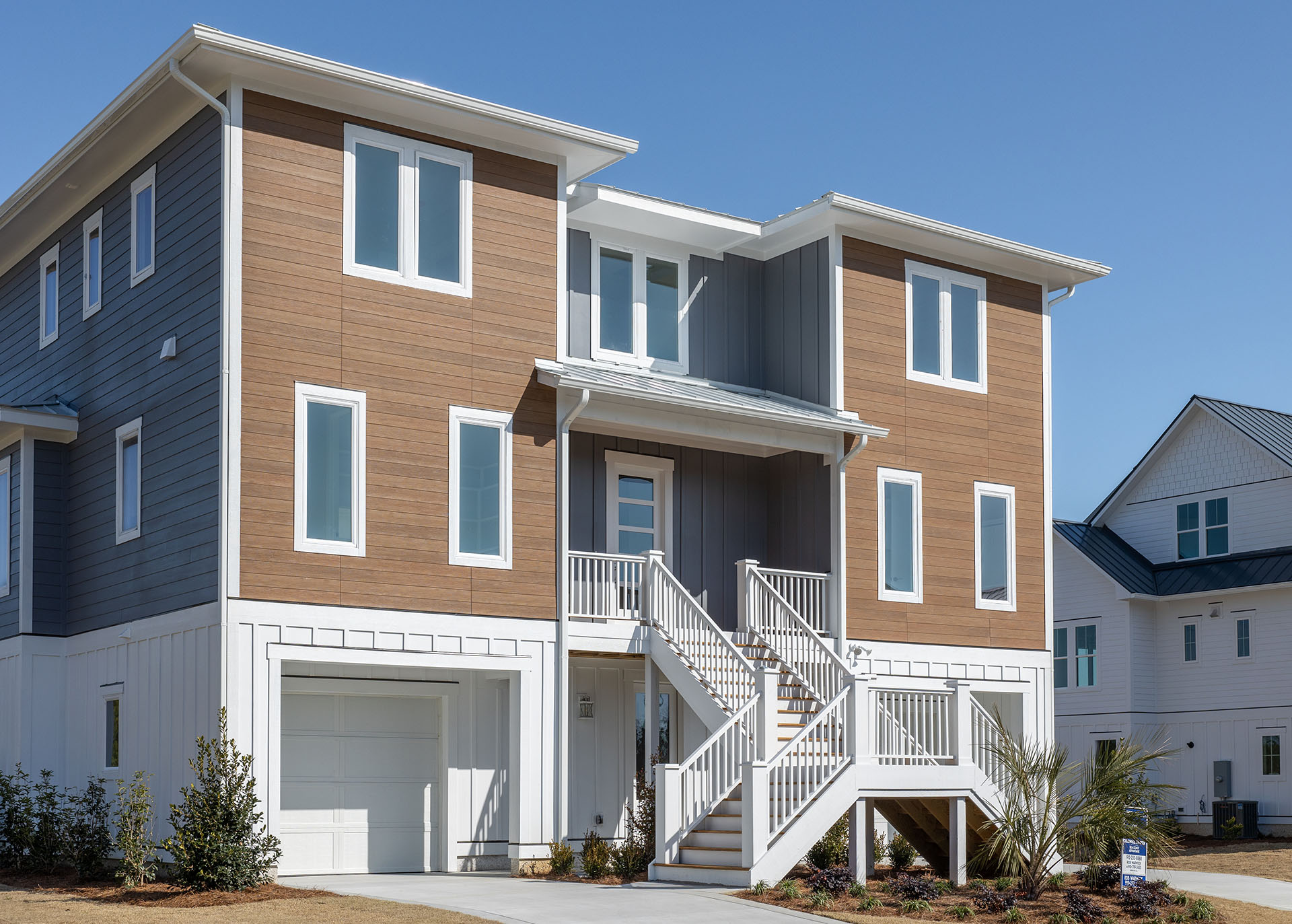 Front exterior of a three-story custom home with fiber cement VintageWood and NichiProducts