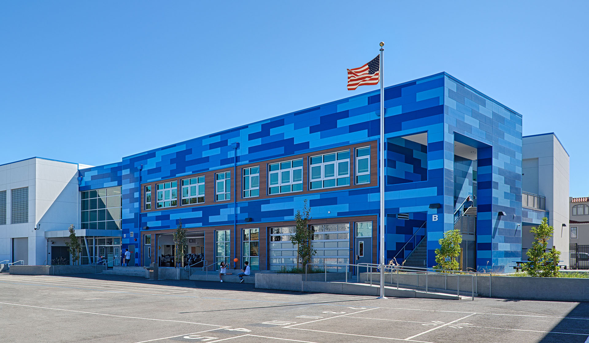 Exterior of Claire Lilienthal school with multiple blue Illumination wall panels and an American flag flying high